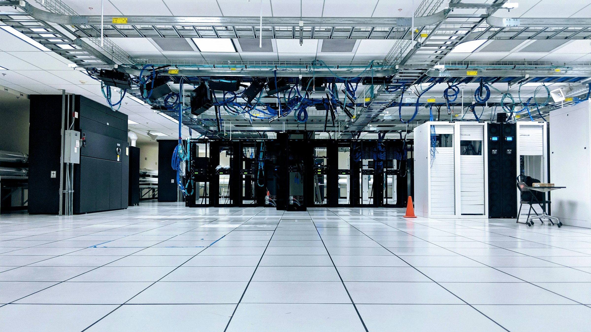 Bright data center hall with rows of server cabinets and overhead cable trays